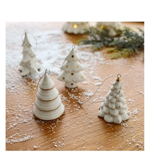 Detailed view of four white ceramic mini Christmas tree ornaments with gold dotted accents