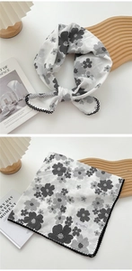 Detail of floral linen square scarf featuring black flower prints and wavy stitched edges