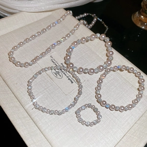 Detail of pearl and rhinestone jewelry set including necklace, bracelets, and ring