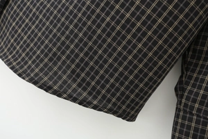 Close-up of high-quality sewing craft and dark gray plaid fabric on casual shirt