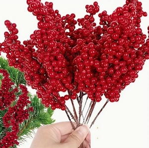 Close-up of hand holding a bunch of vibrant red artificial holly berries for decor
