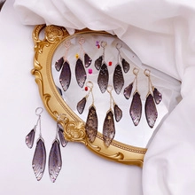 Macro detail of purple gradient cicada wing earrings on a vintage mirror surface