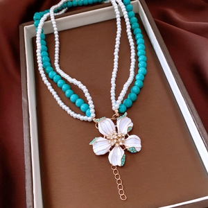 Detail of vintage layered necklace with turquoise beads, pearls and white flower pendant