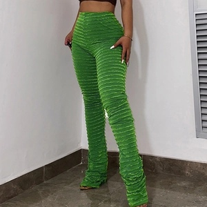 Détail de la texture en maille côtelée verte du pantalon évasé ajusté à taille haute