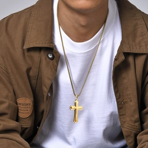 Detail of a man wearing gold triple-layered cross pendant necklaces over a white t-shirt