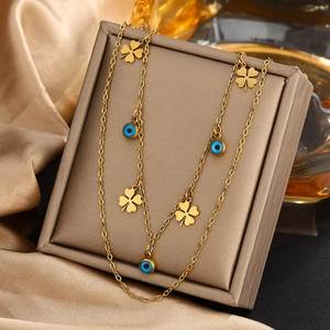 Collier double rang doré avec breloques trèfles et perles œil de protection sur du satin
