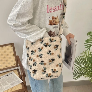 Detail of plush crossbody bucket bag with brown floral pattern and wide shoulder strap