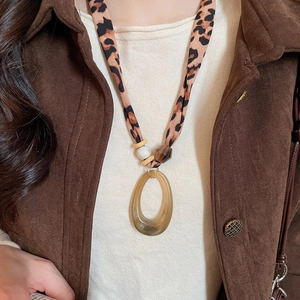 Detail of leopard print fabric strap and amber acrylic pendant on ethnic necklace