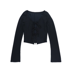 Detail of black waffle knit long sleeve top featuring front lace-up tie closure