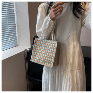 Detail of checkered linen handbag with orange and blue pattern and rope handle