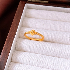 Détail d'une bague dorée vintage avec motifs Ruyi et zircons sur support en lin