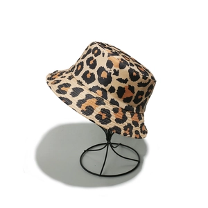 Close-up of leopard print bucket hat on a metal stand with classic brown pattern