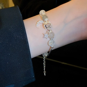 Detail of beaded bracelet with moon star charms and synthetic cat eye stones