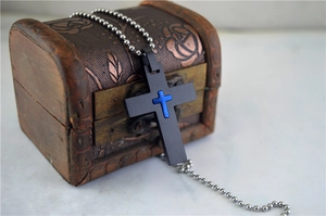 Macro shot of black gothic cross pendant with blue inlay on retro wooden chest display