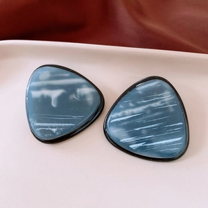 Close-up of vintage resin triangle earrings with blue marble texture on a display tray