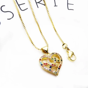Macro shot of gold-plated heart pendant with colorful micro-set zircons on box chain