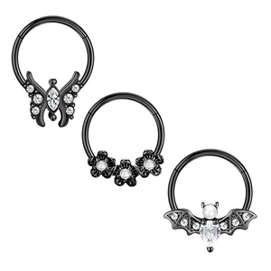 Detailed macro view of black nose rings with butterfly, flower, and bat zircon designs