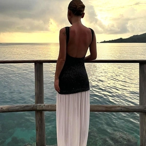 Detail of sexy backless sequin top and white pleated maxi dress on a seaside boardwalk