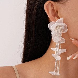 Close-up of handmade white lace flower earrings with delicate silver beaded tassels