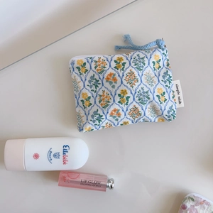 Flat lay of small floral cotton coin purse with blue checkered patterns and cosmetics