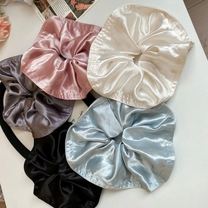 Detailed flat lay of five assorted silk satin scrunchies in soft pastel color tones