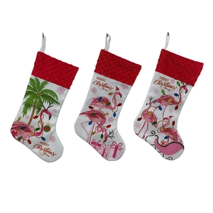 Three white Christmas stockings with pink flamingo patterns and red plush cuffs hanging