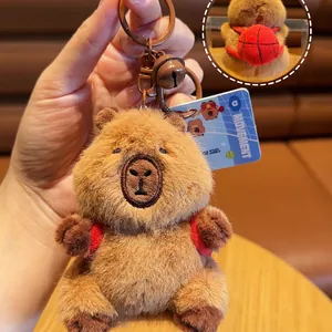 Plush capybara keychain featuring a red basketball backpack with brown metal clasp and bell