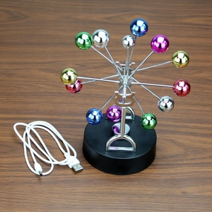 Detail of Newton's cradle with colorful metal balls and USB cable on wooden desk