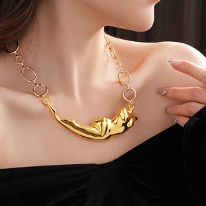 Détail d'un pendentif abstrait doré en forme de corps féminin sur une chaîne polie