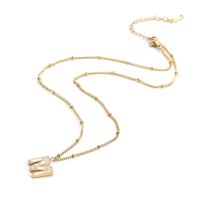 Gold beaded chain necklace featuring a white mother-of-pearl M letter pendant on white background