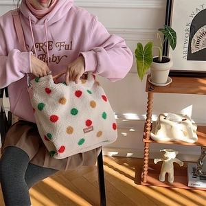 Detailed view of a colorful polka dot plush tote bag held by a model in warm sunlight