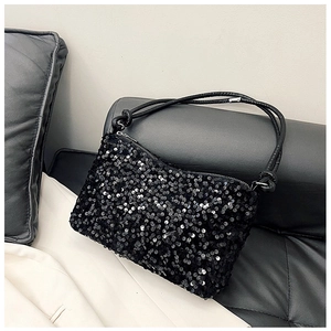 Detail view of shimmering black sequins and slim leather strap on this baguette bag