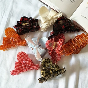 French style acetate ribbon bow hair claws in various patterns on a white cloth background