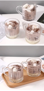 Close-up of coffee-style scented candles in striped glass jars on a wooden tray