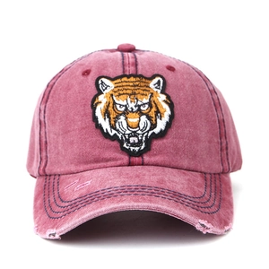 Detail of tiger head embroidery and distressed brim on washed red vintage baseball cap