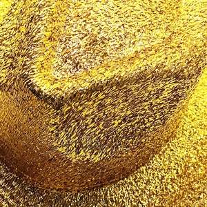 Macro detail of high-shine gold sequin fabric with metallic woven texture for western hats