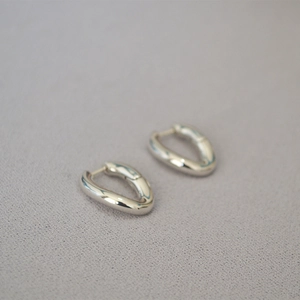 Detalle de los aros ovalados plateados pulidos con un acabado metálico minimalista