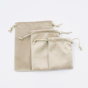 Trio of beige velvet drawstring pouches in small medium and large sizes on white background