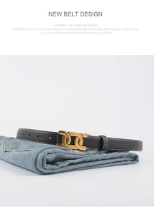 Détail de la ceinture en cuir grainé noir avec boucle dorée à double anneau sur jean
