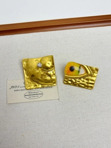 Detail of vintage gold-tone earrings with hammered texture and eye-shaped emerald design