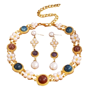 Detailed flat lay of vintage gold jewelry set with pearls and colorful cabochons