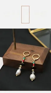 Macro detail of vintage baroque pearl earrings with black agate and 18k gold plating