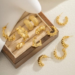 Close-up of assorted 18k gold plated C-shaped earrings with textured metallic finish