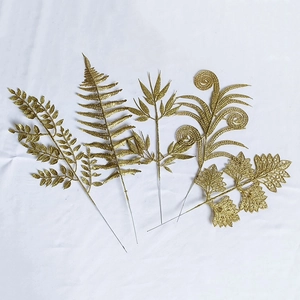 Detail of assorted golden glitter artificial leaves for Christmas decor on white fabric