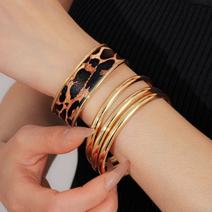 Vue détaillée du bracelet en cuir imprimé léopard et des anneaux empilables en métal doré