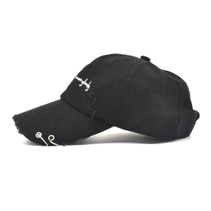 Close-up of distressed black cotton baseball cap with iron rings and white embroidery
