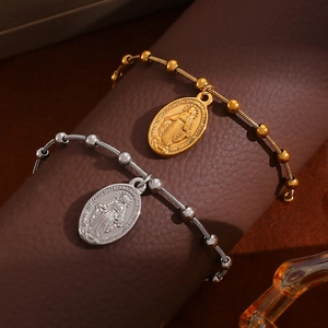 Detail of gold and silver Virgin Mary religious oval pendant bracelets with metal beads