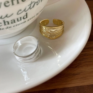 Minimalist 925 sterling silver wavy open rings in gold and silver finish on a ceramic plate