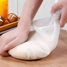 Handen die deeg kneden in een flexibele witte siliconen mengzak op houten plank