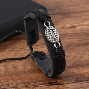 Detail of multi-layer black leather bracelet featuring silver American football charm decoration
